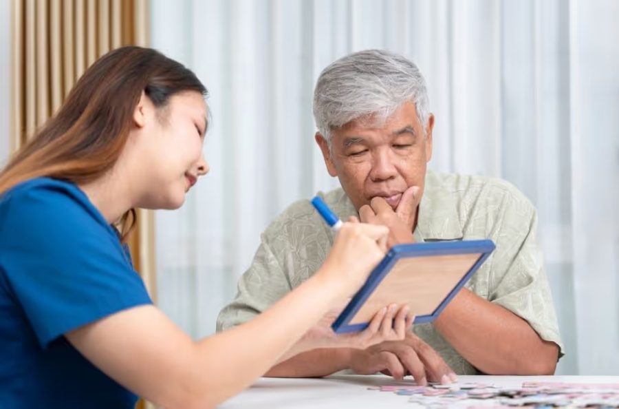 Profissional acompanhando um senhor em um exercício cognitivo no tablet